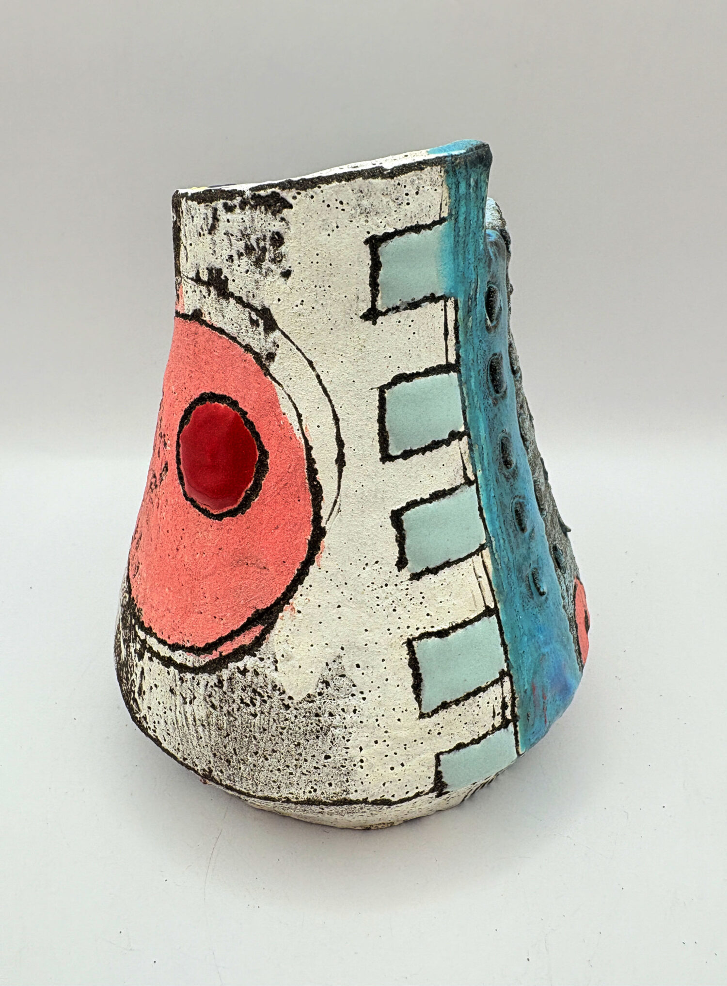 Small vessel with red circle and green drip